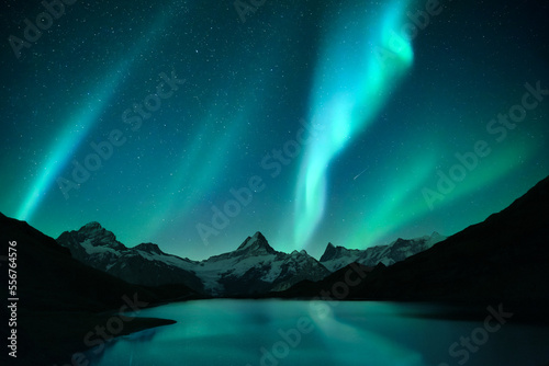 Aurora borealis. Northern lights in winter mountains. Sky with polar lights and stars. Stars reflection in lake water