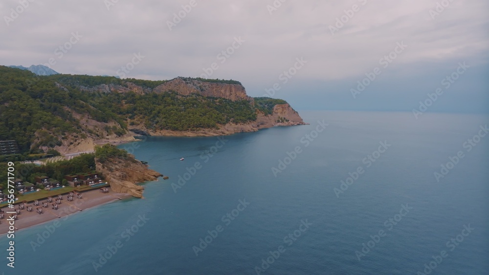Natural landscape. Aerial drone view of a beach in a blue bay. Rocky coast. Green trees on the rocks. 