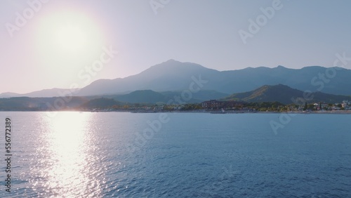 Aerial view flight over the blue sea at sunset. Beautiful clouds. Mountains in the background. Seascape. Photography