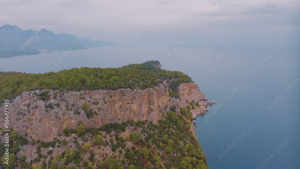 Natural landscape. Aerial drone view of a beach in a blue bay. Rocky coast. Green trees on the rocks. 