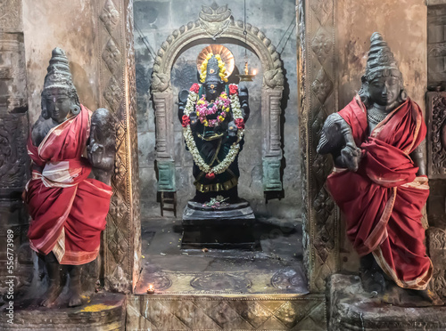 Alcove with Hindu deity statue in wall with guardian statues wrapped in silk on either side at the Dravidian Chola era Airavatesvara Temple; Darasuram, Tamil Nadu, India