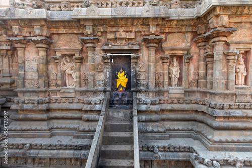 Stairs leading to an alcove with Hindu deity statue wrapped in bright yellow silk in a stone wall of the Dravidian Chola era Airavatesvara Temple; Darasuram, Tamil Nadu, India photo
