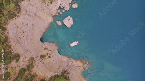 Top view of a rocky shore covered with green trees. Cave in the rock. The boat is near the shore. Aerial drone view photo