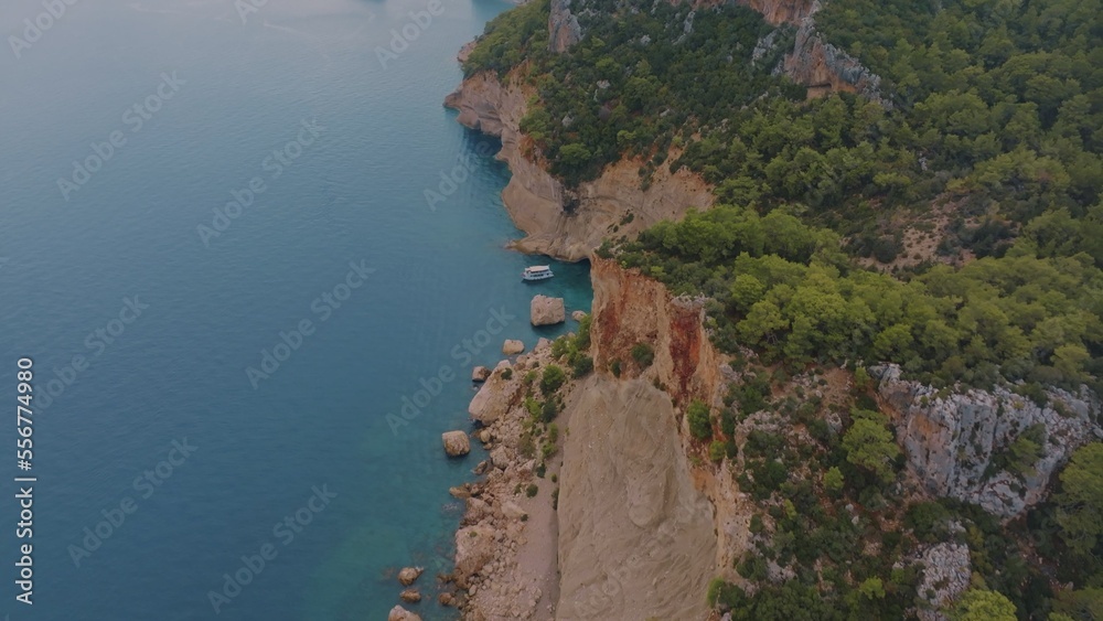 Beautiful seascape. Top view of a rocky shore covered with green trees. Blue water. Aerial view. Photography