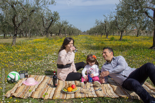 Image of a smiling family sitting in a flowery field having a picnic. Holiday in Tuscany Italy family enjoying relaxing in the open countryside.  © gianni