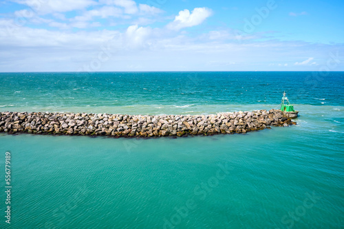 Close-up of a rock breakwater and boat moored at the end in the green water of the North Sea along the coast of Denmark; Hirtshals, Jutland, Denmark photo