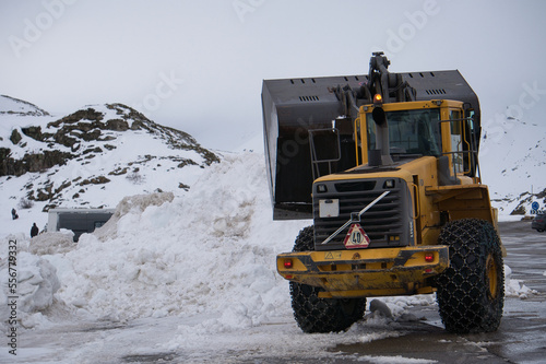Quitanieves con cadenas amontonando nieve de la carretera. Máquina excavadora quitando nieve