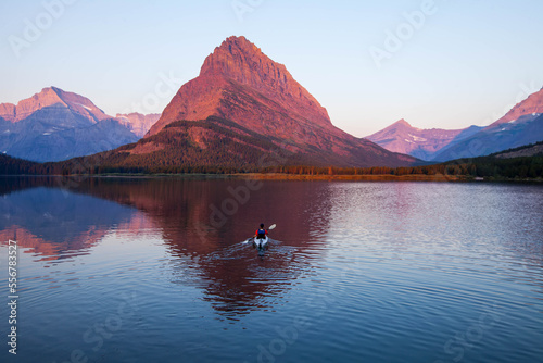 A kayaker on Swiftcurrent Lake watches the sunrise over Mount Grinnell. photo