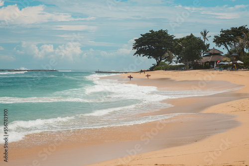 Surfers standing on the beach at the water's edge waiting for the waves at Geger Beach in the Nusa Dua resort area; Geger Beach, Badung, Bali, Indonesia photo