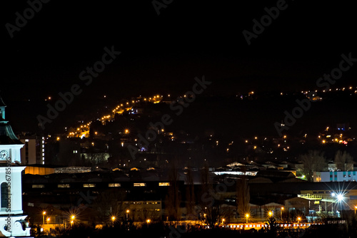 Ostrowiec Świętokrzyski nocą . Widok miasta z góry . Zabudowania starej huty , światła miasta . Oświetlona droga wspinająca się na wzgórza . © Grzegorz