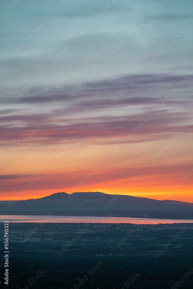 The sun sets above Mt. Susitna, or Sleeping Lady, across Cook Inlet from downtown Anchorage, Alaska on Dena’ina land, with Knik arm in view; Alaska, United States of America The sun sets above Mt. Susitna, or Sleeping Lady, across Cook Inlet from downtown Anchorage, Alaska on Dena’ina land, with Knik arm in view; Alaska, United States of America