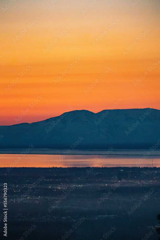 The sun sets above Mt. Susitna, or Sleeping Lady, across Cook Inlet from downtown Anchorage, Alaska on Dena’ina land, with Knik arm in view; Alaska, United States of America The sun sets above Mt. Susitna, or Sleeping Lady, across Cook Inlet from downtown Anchorage, Alaska on Dena’ina land, with Knik arm in view; Alaska, United States of America
