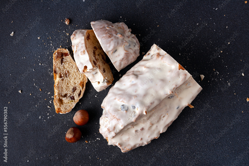 Christmas bread - stollen with nuts and dried fruits on a wooden board, on a dark background, flat lay
