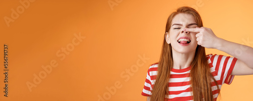 Silly childish redhead girl fool around, make piggy nose, show tongue immature carefree, having fun, playful enthusiastic mood, stand upbeat show nostrils happily grinning, orange background photo