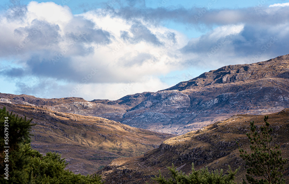 Harsh Scottish mountain range softened and enriched by shafts of autumn light; Strathcarron, Highland, Scotland