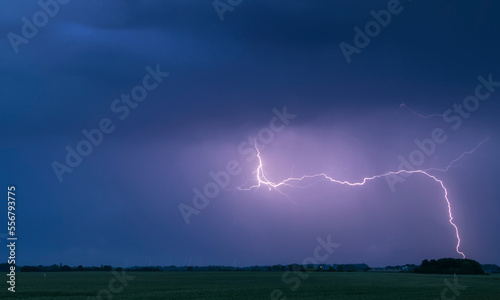 A lightning bolt arcs out of the base of a dark storm cloud and strikes the ground; Lincolnshire, England