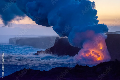Hot lava illuminates a huge column of noxious gas at the blue hour as it enters the ocean on the Big Island of Hawaii; Hawaii, United States of America photo