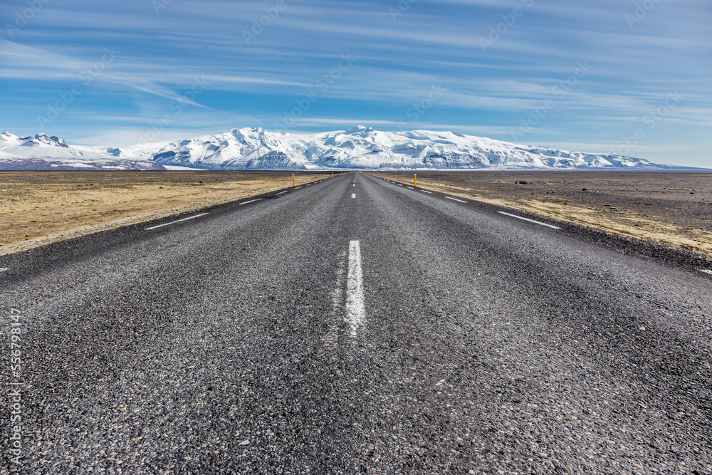 strada rettilinea islandese con sullo sfondo una montagna coperta di ghiaccio