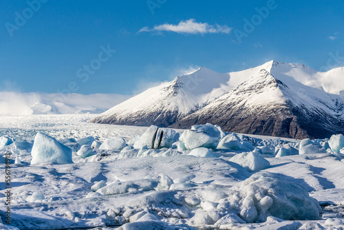 la laguna da scioglimento del ghiacciaio Jökulsárlón colma di iceberg con una montagna innevata, cielo azzurro e una nuvola photo