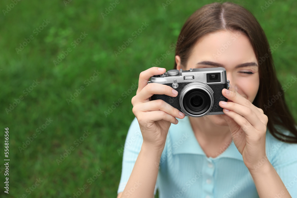 Young woman with camera taking photo outdoors, space for text. Interesting hobby Young woman with camera taking photo outdoors, space for text. Interesting hobby