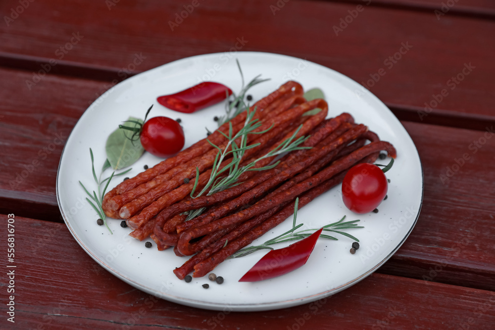Tasty dry cured sausages (kabanosy) and ingredients on wooden table Tasty dry cured sausages (kabanosy) and ingredients on wooden table