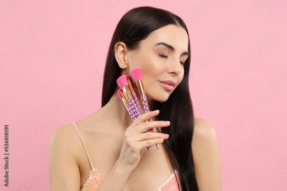 Beautiful woman with different makeup brushes on pink background Beautiful woman with different makeup brushes on pink background