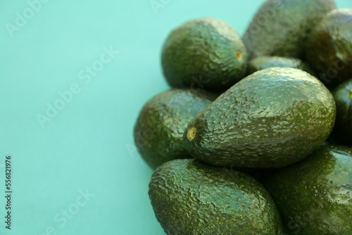 Many tasty ripe avocados on turquoise background. Space for text