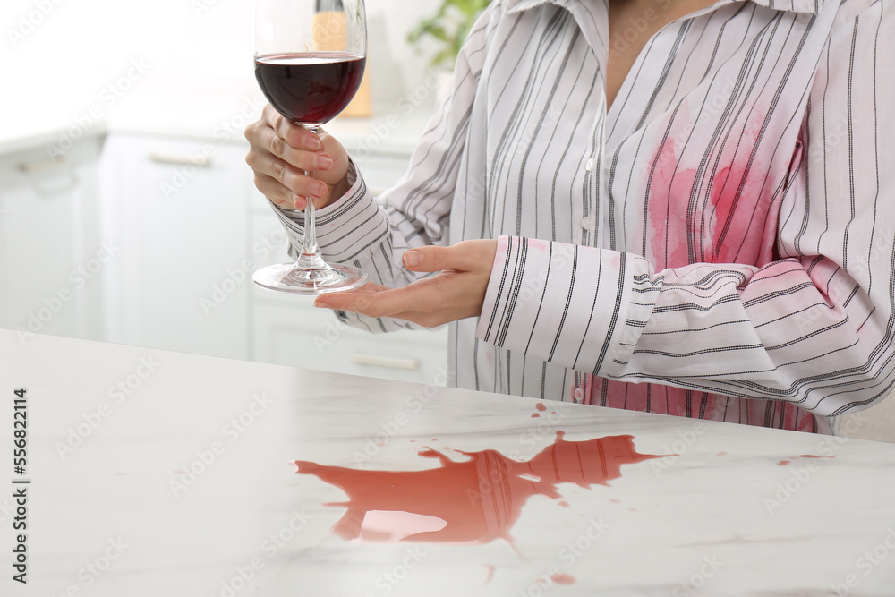 Woman with spilled wine over her shirt and marble table in kitchen, closeup - obrazy, fototapety, plakaty 