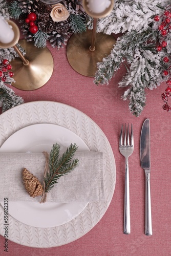 Festive place setting with beautiful dishware, cutlery and cone for Christmas dinner on pink tablecloth, flat lay