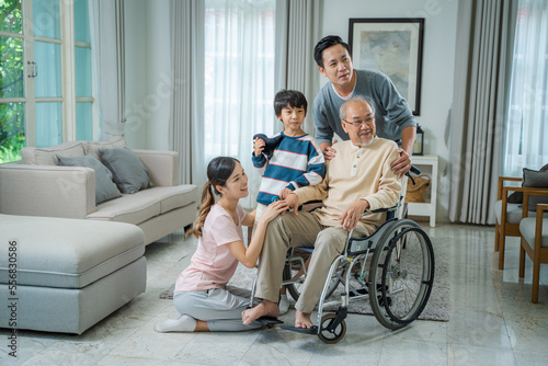 Asian senior male sitting at wheelchair with family at home living room,Retired older people,Concept healthcare.