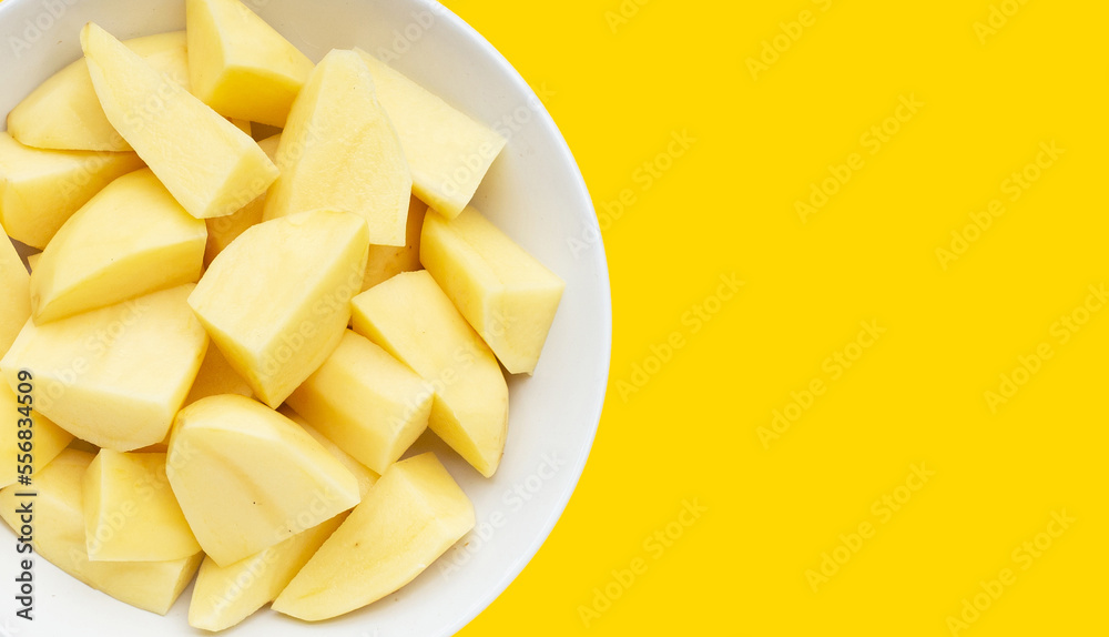 Raw peeled potatoes on yellow background Raw peeled potatoes on yellow background