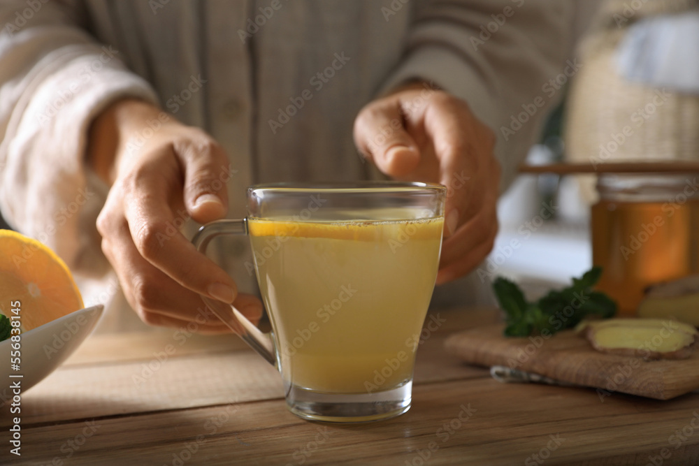 Woman making aromatic ginger tea at wooden table indoors, closeup Woman making aromatic ginger tea at wooden table indoors, closeup