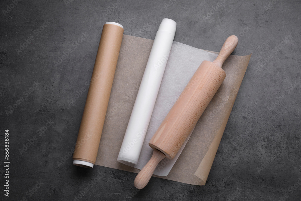 Rolls of baking paper and rolling pin on dark grey table, top view Rolls of baking paper and rolling pin on dark grey table, top view
