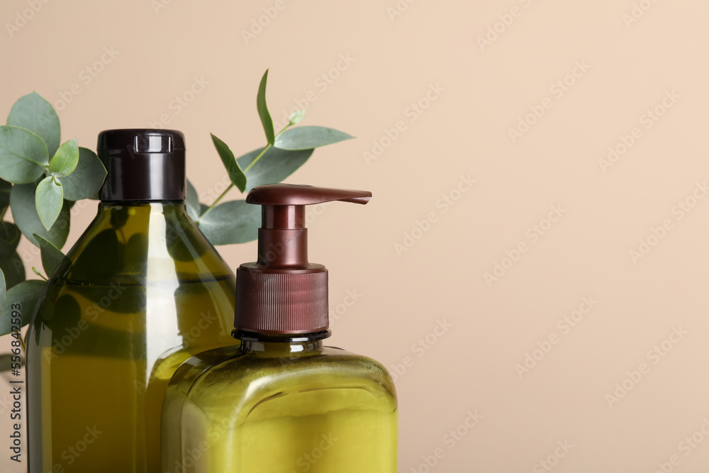 Bottles of shampoo near beige wall, closeup. Space for text Bottles of shampoo near beige wall, closeup. Space for text