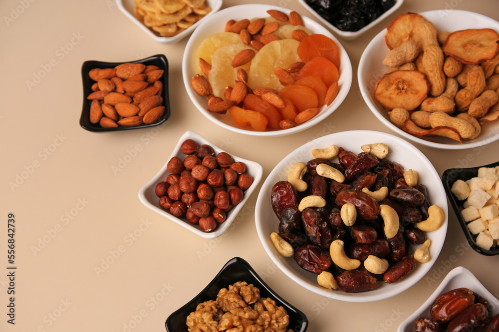 Bowls with dried fruits and nuts on beige background, above view. Space for text Bowls with dried fruits and nuts on beige background, above view. Space for text