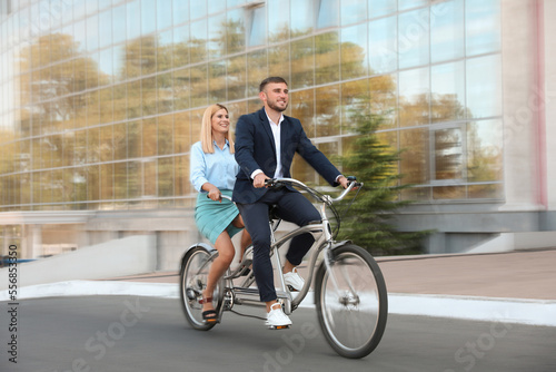 Couple riding tandem bike on city street, motion blur effect