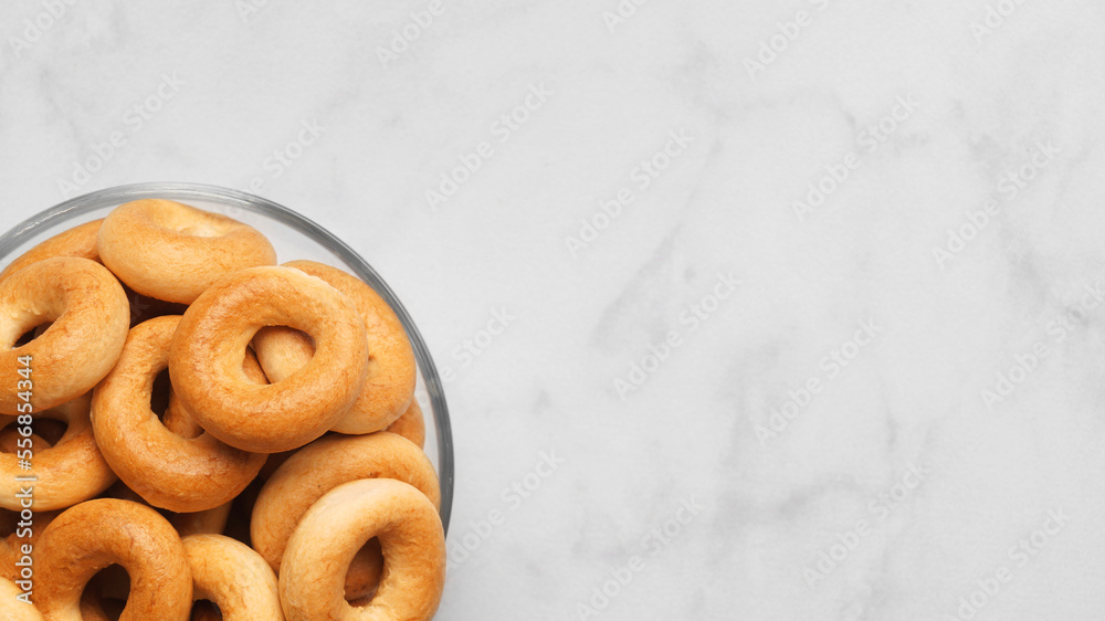 Bowl of tasty dry bagels (sushki) on white marble table, top view. Space for text Bowl of tasty dry bagels (sushki) on white marble table, top view. Space for text
