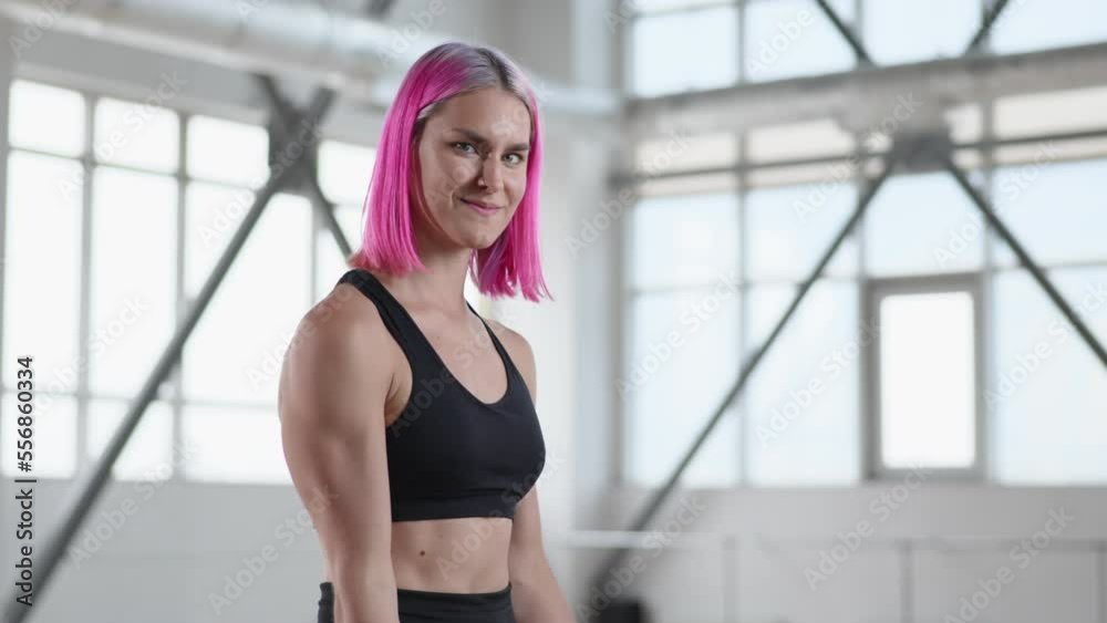 Portrait of a girl performing strength workout while training alone in bright gym studio. Cheerful female athlete smiling while doing dumbbell exercises. High quality 4k footage Portrait of a girl performing strength workout while training alone in bright gym studio. Cheerful female athlete smiling while doing dumbbell exercises. High quality 4k footage