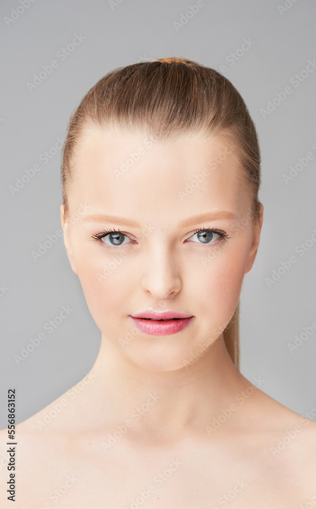 Portrait of attractive blond Caucasian girl with high ponytail and soft makeup looking at camera on white background Portrait of attractive blond Caucasian girl with high ponytail and soft makeup looking at camera on white background