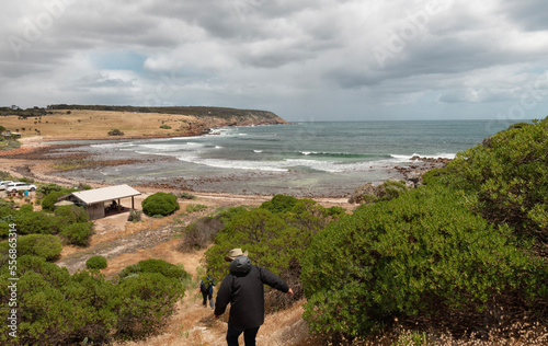 View of Stokes Bay, Kangaroo Island, South Australia. A man with a hat is seen from behind walking down to the beach on a cloudy day.