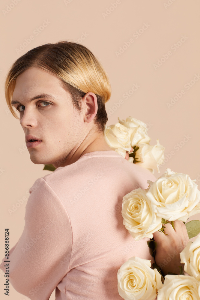 Caucasian male model in pink outfit with white roses turning back Caucasian male model in pink outfit with white roses turning back