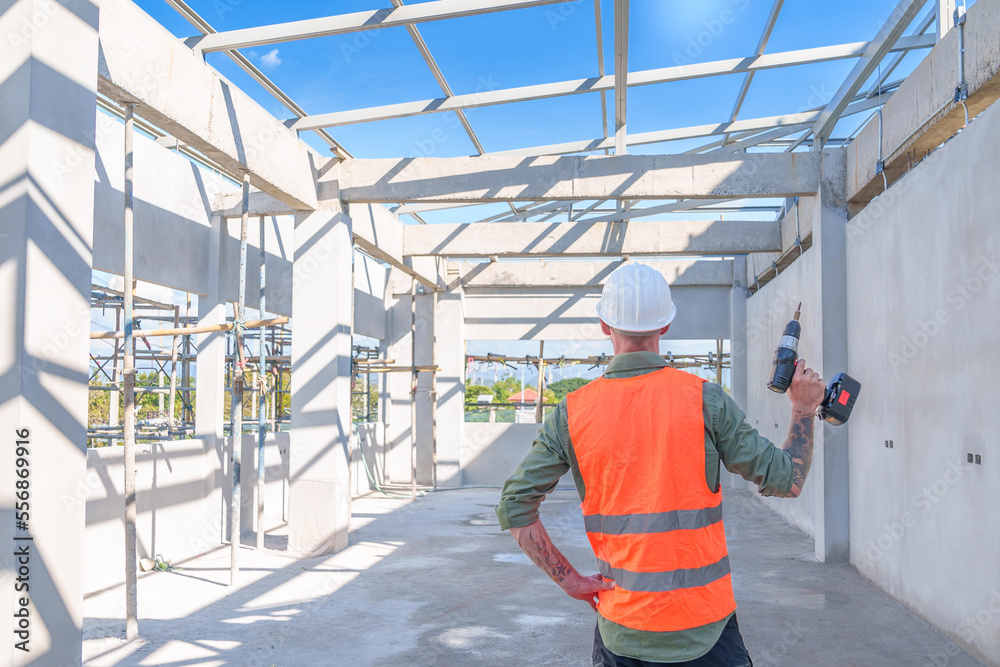 Male engineer wearing safety suit and hard hat holding toolbox and electric drill in construction site for building site survey in civil engineering project.