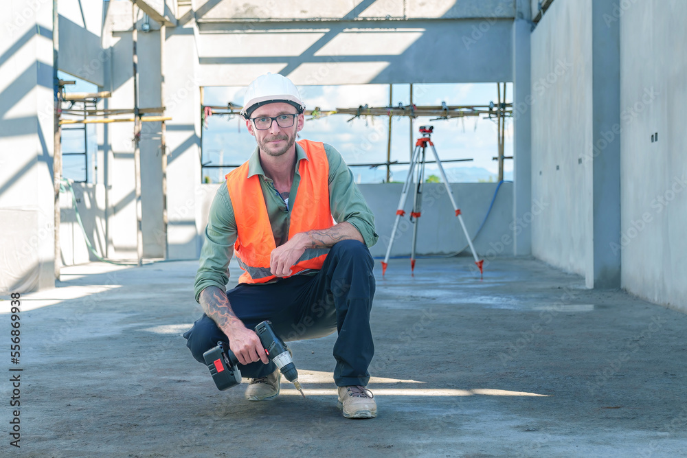 Male engineer wearing safety suit and hard hat holding toolbox and electric drill in construction site for building site survey in civil engineering project. Male engineer wearing safety suit and hard hat holding toolbox and electric drill in construction site for building site survey in civil engineering project.