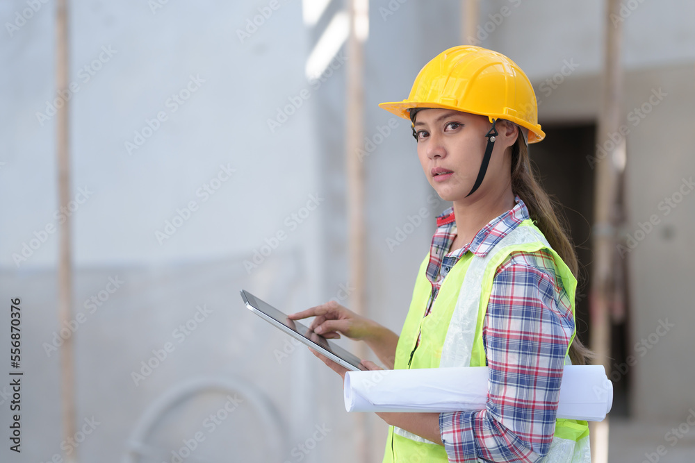 Fototapeta premium Asia Female civil engineer with inspecting construction plans at building site of high-riser building site survey in civil engineering project.