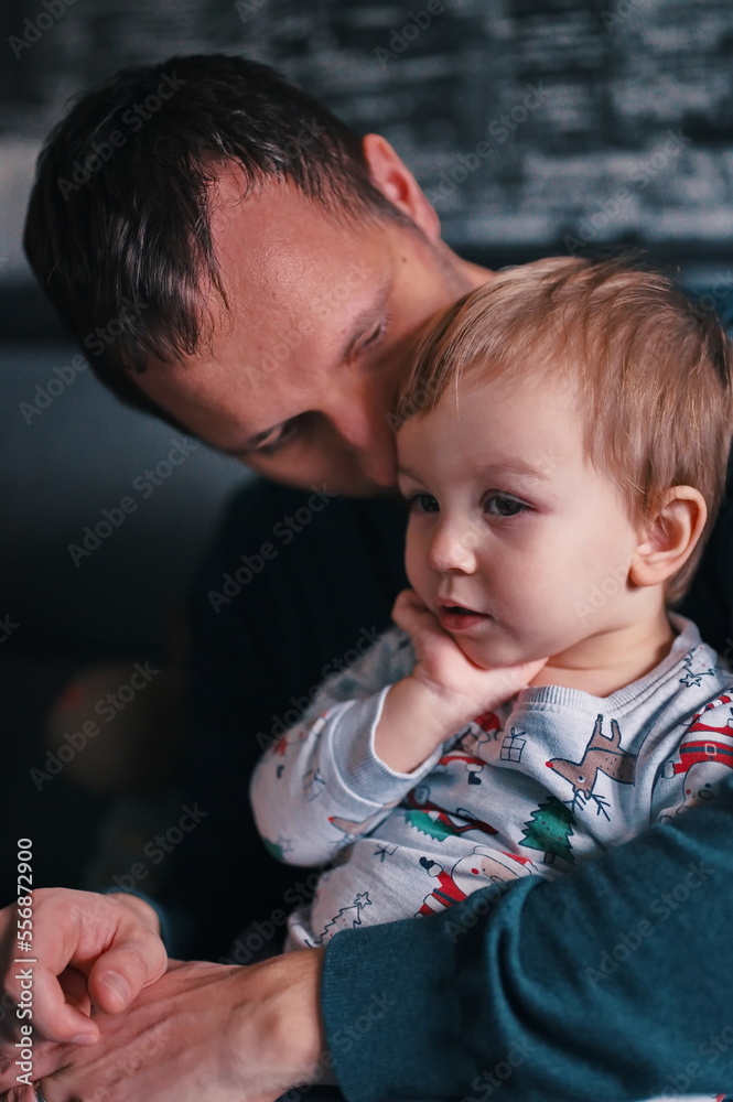 Father sitting on a sofa and holding his little boy Father sitting on a sofa and holding his little boy