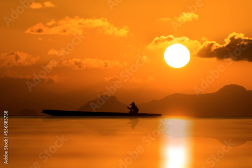 Silhouette of fishermen on the lake with sunset sky.