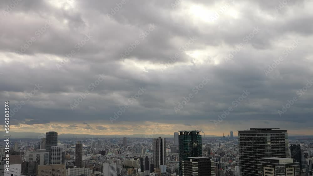 Overhead view of Osaka's Umeda area from a hill on a cloudy day, sunlight shining through a gap in the clouds. Overhead view of Osaka's Umeda area from a hill on a cloudy day, sunlight shining through a gap in the clouds.