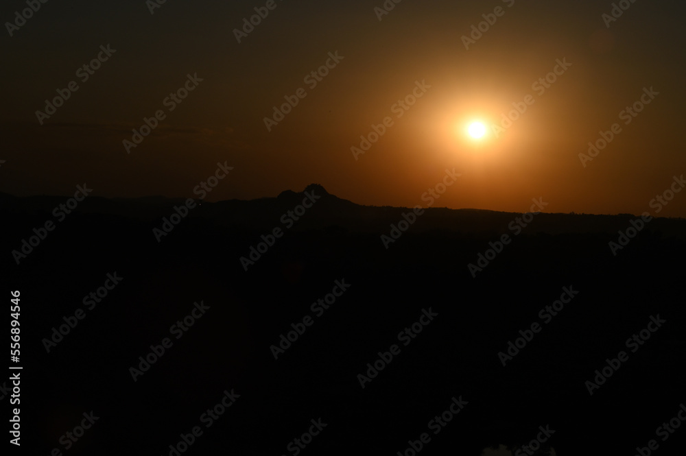 Silhouette image of a hill. Image of a Sunset behind the hill Silhouette image of a hill. Image of a Sunset behind the hill