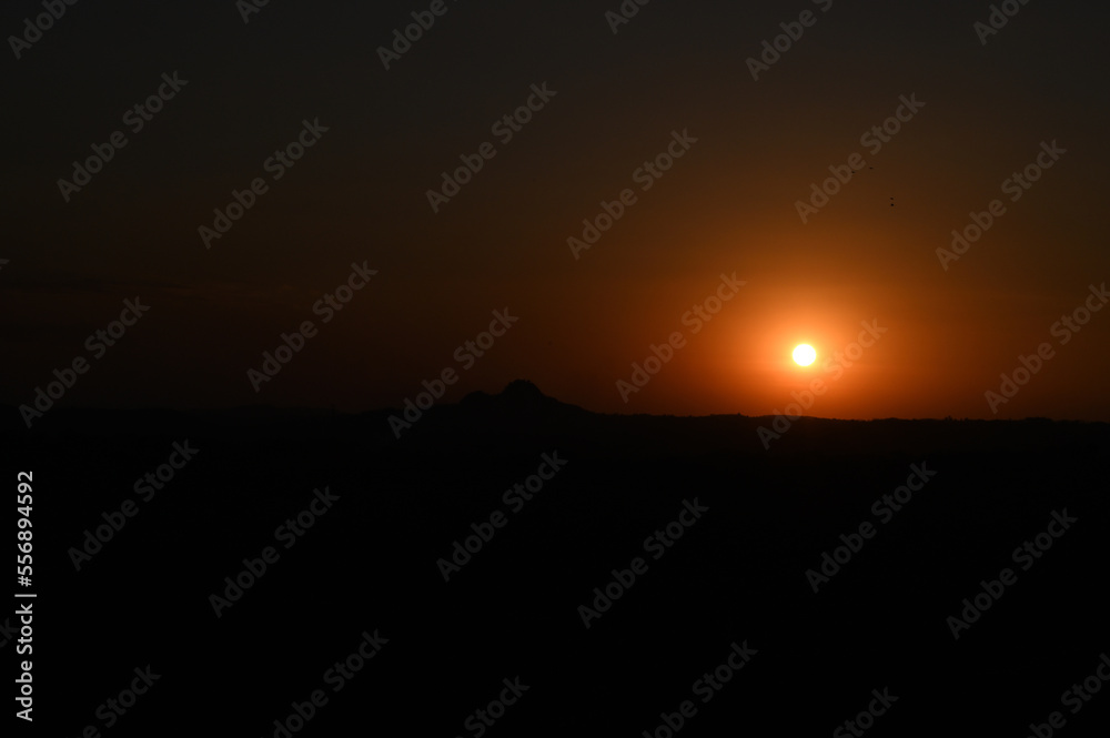 Silhouette image of a hill. Image of a Sunset behind the hill Silhouette image of a hill. Image of a Sunset behind the hill