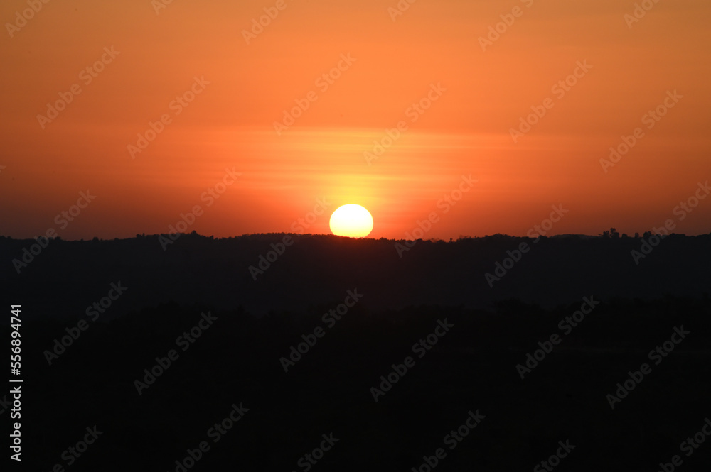 Silhouette image of a hill. Image of a Sunset behind the hill Silhouette image of a hill. Image of a Sunset behind the hill